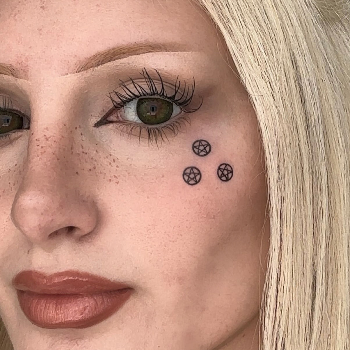 Black pentagram design stamp used in a graphic makeup look
