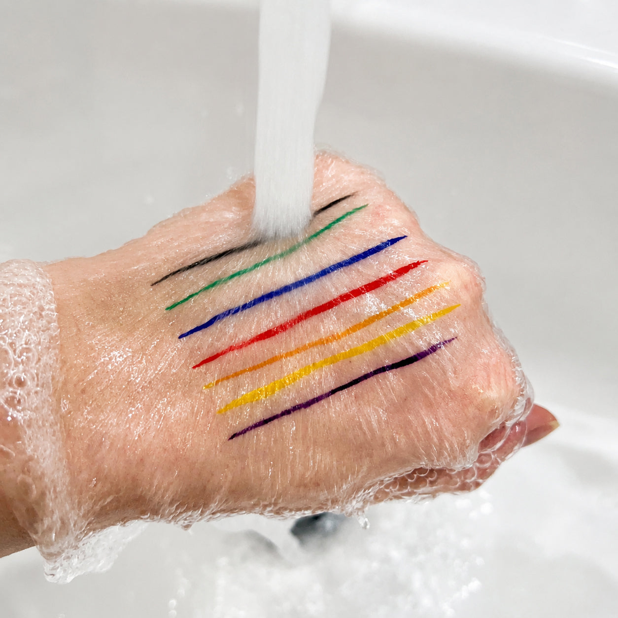 Colorful Sunset Makeup eyeliner swatches on a hand under running water, doing water resistant test.