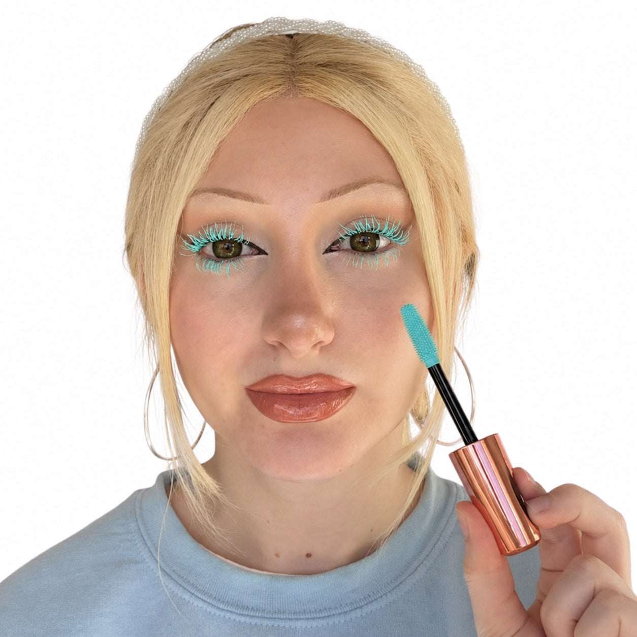 Model wearing pastel blue mascara on upper and lower lashes while holding the matching mascara wand against a white background.