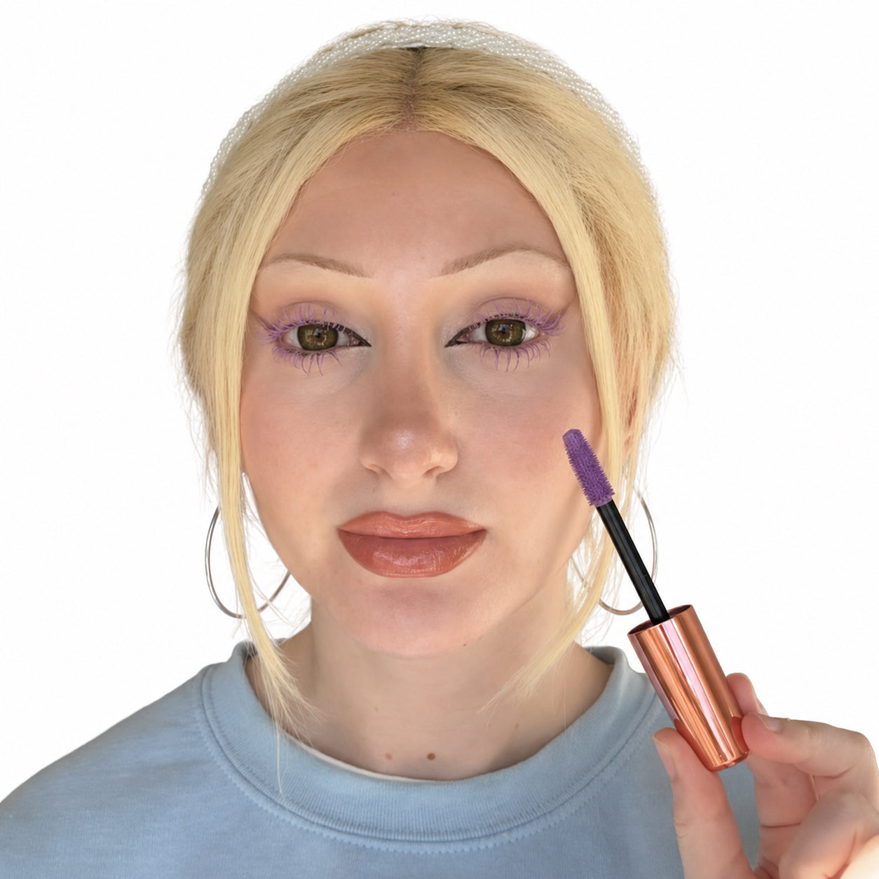 Model wearing pastel purple mascara on upper and lower lashes while holding the matching mascara wand against a white background.