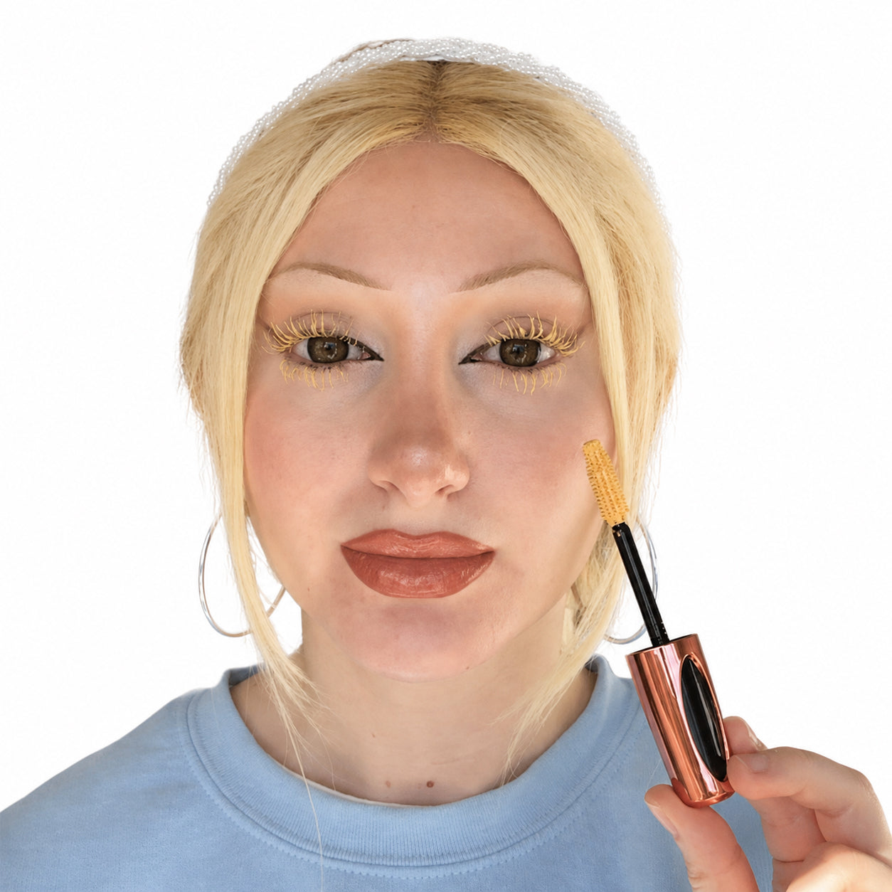 Model wearing pastel yellow mascara on upper and lower lashes while holding the matching mascara wand against a white background.